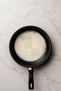 simmering-heavy-cream-in-black-skillet-for-keto-alfredo-sauce