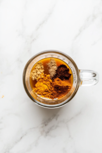 This image shows whole milk being gently heated in a shiny stainless steel saucepan over a white marble cooktop, with no additional items in the scene.
