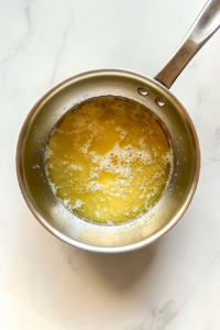 warming-butter-and-milk-in-small-silver-saucepan-on-white-marble