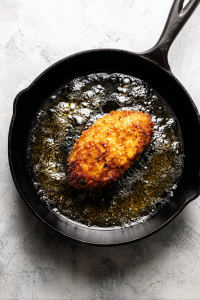 flipped-chicken-frying-in-cast-iron-skillet