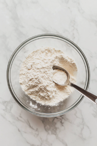 This image shows a top-down view of a mini cupcake pan lined with pastel cupcake liners placed on a white marble countertop, ready for baking.
