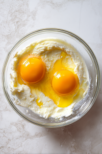 adding-eggs-to-creamed-mixture-in-glass-bowl