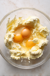 adding-eggs-to-pound-cake-batter-in-glass-bowl