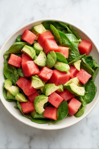 adding-watermelon-avocado-spinach-to-white-ceramic-salad-bowl