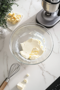 beating-butter-cream-cheese-in-glass-bowl-on-white-marble