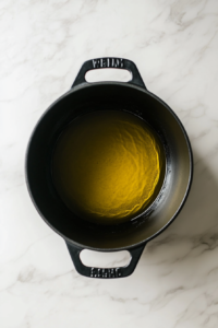 black-dutch-oven-with-olive-oil-on-white-marble-cooktop