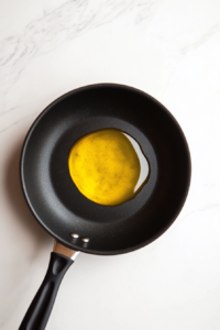 black-nonstick-skillet-with-olive-oil-heating-white-marble