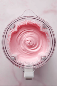 blending_fruit_mixture_until_smooth_in_glass_blender_on_white_marble