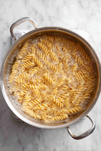 boiling-fusilli-pasta-in-silver-pot-on-white-marble