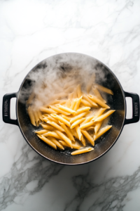 boiling-penne-pasta-in-black-pot-on-marble-cooktop