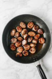 browned-sausage-in-black-skillet-over-white-marble