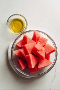 brushing-watermelon-with-olive-oil-on-white-marblebrushing-watermelon-with-olive-oil-on-white-marble