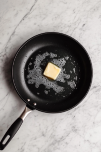 butter-melting-in-black-skillet-on-white-marble