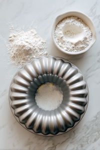 buttering-and-flouring-bundt-pan-on-white-marble