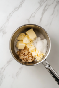 caramel-ingredients-melting-in-saucepan-on-white-marble