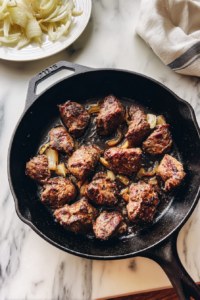 chicken-livers-added-to-black-skillet-onions-set-aside-white-marble