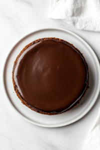 This image shows the chocolate cheesecake mixture spread evenly in a silver springform pan, ready to be frozen, sitting on a clean white marble countertop.
