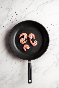 cooking-seasoned-shrimp-in-black-skillet-on-marble