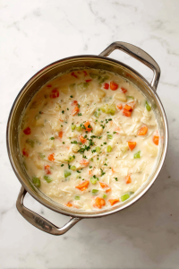 corn-and-shredded-cheddar-added-to-chowder-in-glass-pot