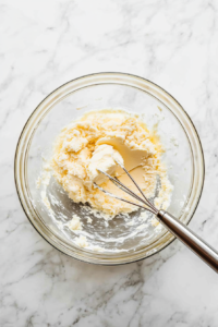 creaming-butter-and-brown-sugar-in-glass-bowl-on-white-marble