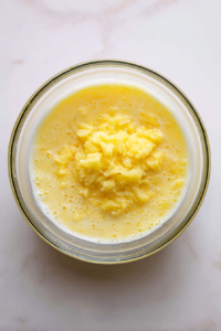 crushed-pineapple-added-to-egg-sugar-mixture-in-glass-bowl