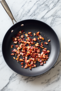 diced-bacon-cooking-in-black-skillet-over-marble-top