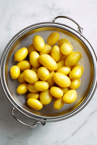 drained-boiled-potatoes-cooling-in-colander-on-white-marble