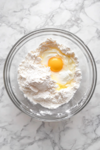 eggs-and-sour-cream-being-mixed-into-dry-ingredients-glass-bowl