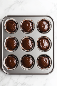 This image shows cupcake liners filled with rich chocolate batter, ready to go into the oven.