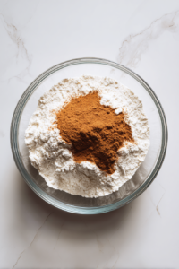 flour-cinnamon-baking-soda-salt-in-glass-bowl-on-marble-countertop