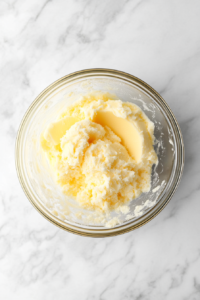 fluffy-mixture-of-butter-oil-and-sugar-in-glass-bowl-on-white-marble