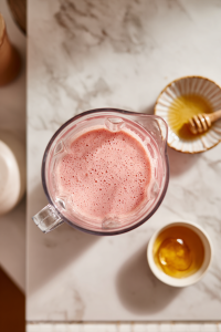 glass_blender_with_smoothie_on_white_marble_and_honey_bowl