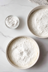 greased-and-floured-round-metal-cake-pans-on-white-marble