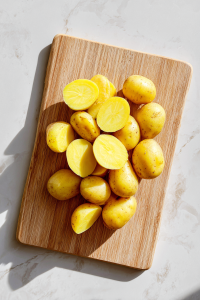 halved-potatoes-on-wooden-cutting-board-white-marble-top