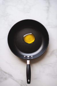 heating-second-tablespoon-of-olive-oil-in-black-skillet-on-marble