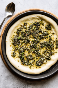 herb-butter-spread-over-pizza-crust-in-black-pan