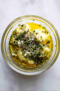 mixing-butter-oil-herbs-in-glass-bowl-on-marble
