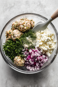 mixing-greek-meatball-ingredients-in-clear-glass-bowl