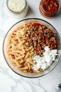 mixing-pasta-with-sausage-sauce-cheese-pepperoni-in-glass-pot