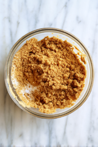 mixing-peanut-butter-and-crumbs-in-clear-glass-bowl-over-white-marble