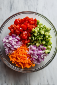 mixing-raw-veggies-in-glass-bowl-on-white-marble