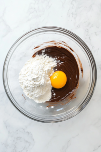 nutella-flour-and-egg-in-glass-bowl-before-mixing-on-white-marble