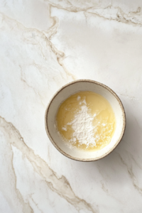 preparing-lemon-glaze-in-white-bowl-on-marble-countertop