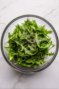 seasoning-arugula-with-salt-pepper-in-glass-bowl