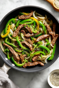 seasoning-steak-and-veggies-in-black-skillet