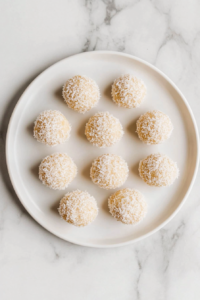 This image shows finished Apple Coconut Bites served on a white ceramic plate placed over a white marble cooktop, ready to be enjoyed.