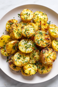 serving-grilled-potatoes-on-white-ceramic-plate-with-herb-garnish-white-marble-background