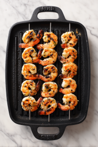 shrimp-skewers-grilling-on-black-pan-on-white-marble