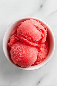 single-serving-of-watermelon-sorbet-in-white-bowl-on-clean-marble