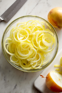 slicing-onions-glass-bowl-white-marble-top-down-prep-shot